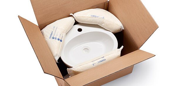 A cardboard box containing a washbasin and foam packaging