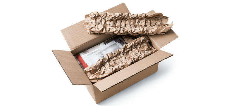 A cardboard box containing a coffee maker and brown paper cushioning