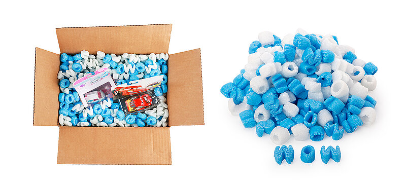 A cardboard box containing children’s toys and blue and white packaging chips in the shape of letters of the alphabet