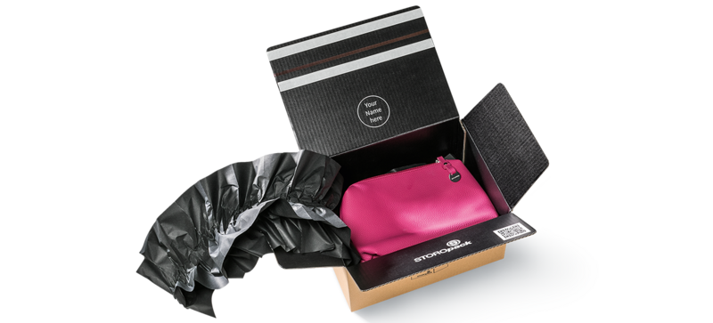 A cardboard box containing a pink bag and black paper cushions