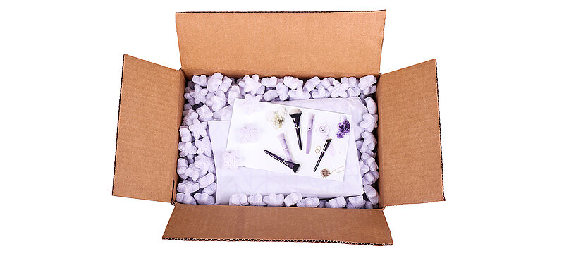 A cardboard box containing cosmetics and purple, star-shaped packaging chips
