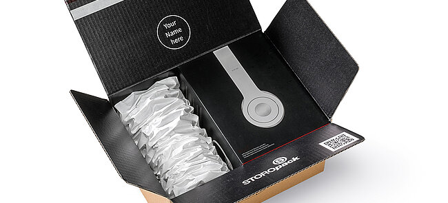 A cardboard box containing headphones and white paper cushioning