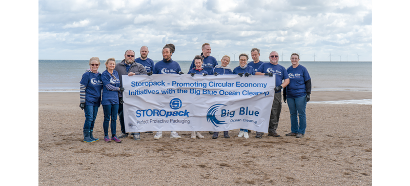 Storopack employees standing behind a banner for the organization Big Blue Ocean Cleanup on the beach