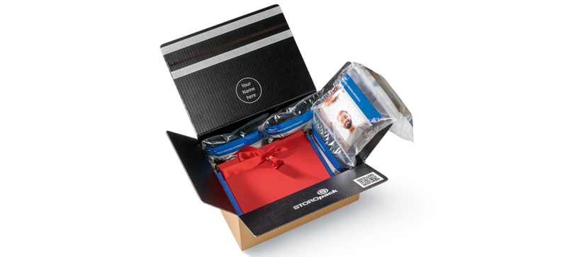A cardboard box containing a red gift box and air cushions with a printed design